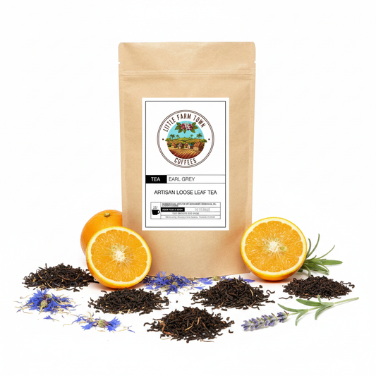 A cup of brewed Earl Grey artisan tea from Little Farm Town Coffees with a tea bag and fresh lemon slices on a white background.